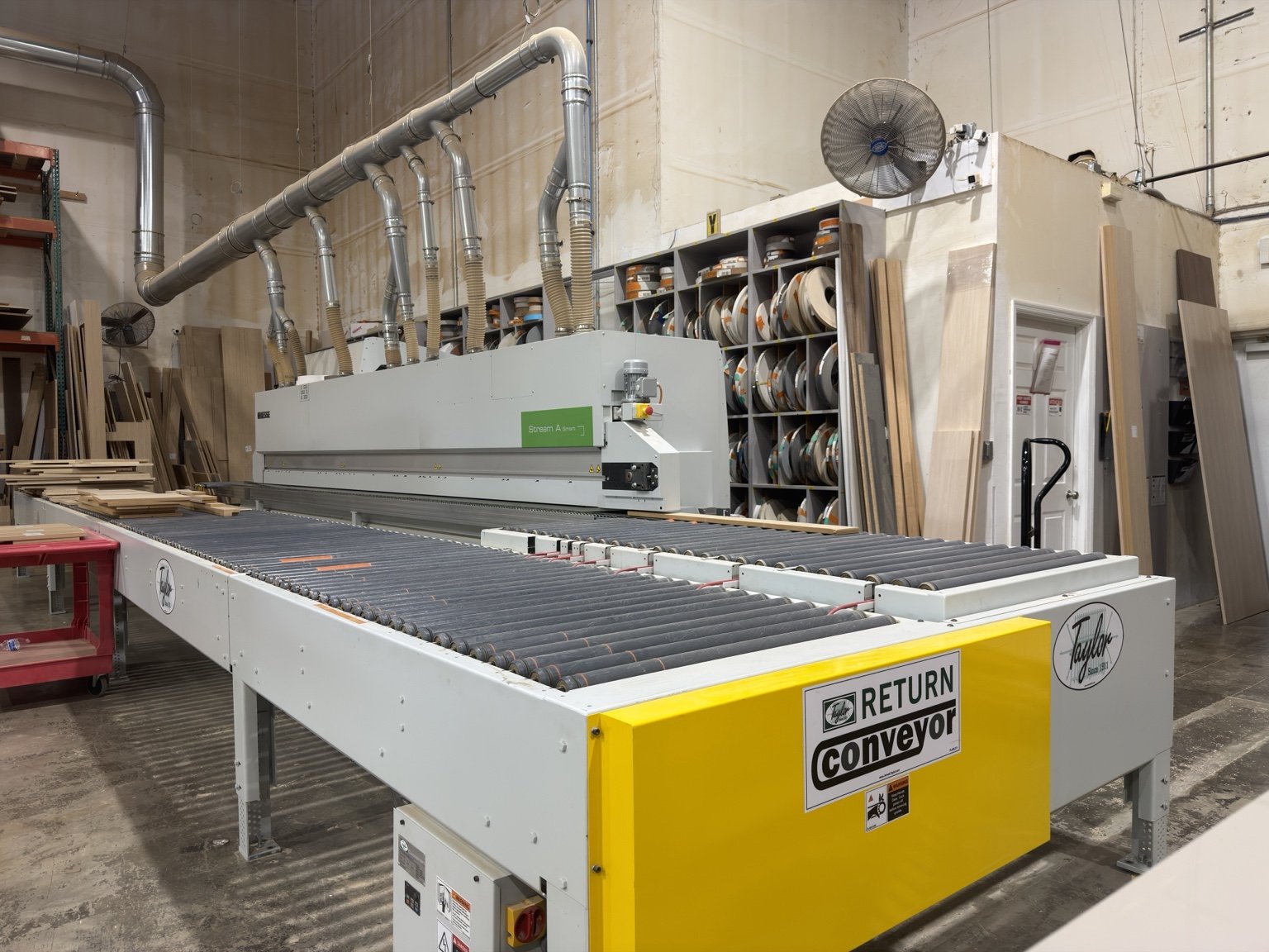 Edgebander with its Taylor return conveyor and a full rack of edgebanding coils behind | Sunshine Alliance, Deerfield Beach FL